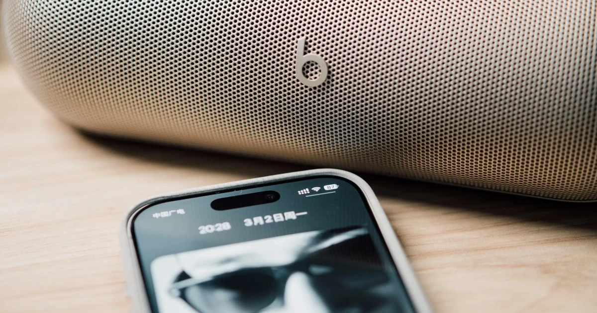 iPhone lying in front of a wireless speaker.