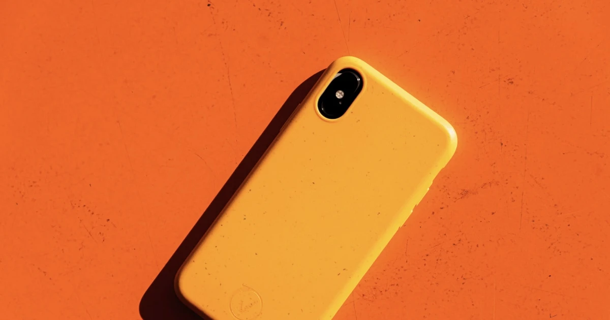 An iPhone with a yellow phone case on an orange background.