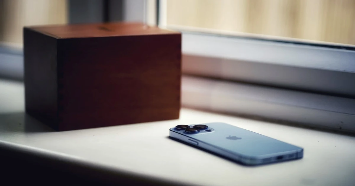 iPhone on a windowsill next to a wooden speaker box.